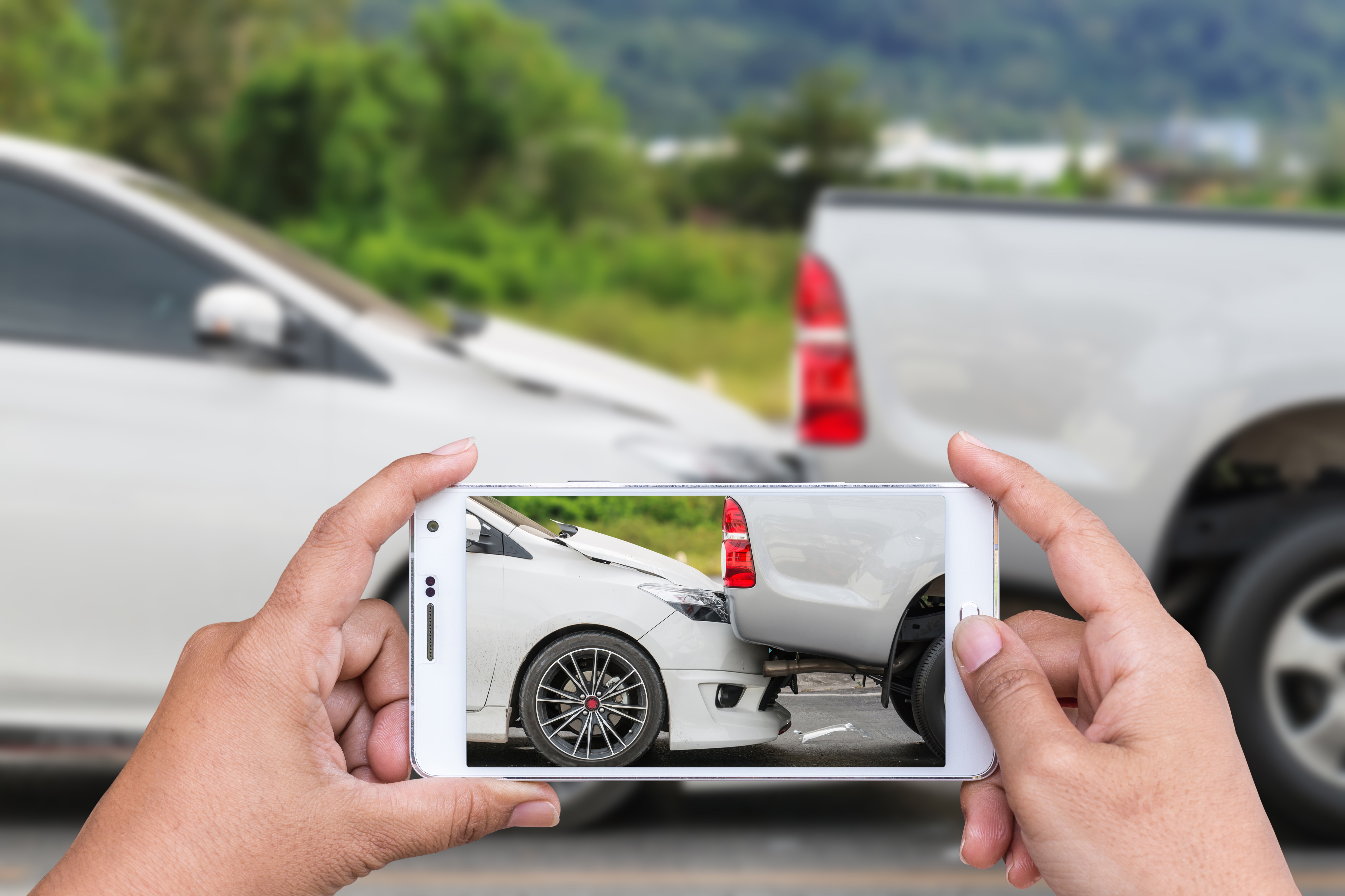 Hand of woman holding smartphone and take photo of car accident